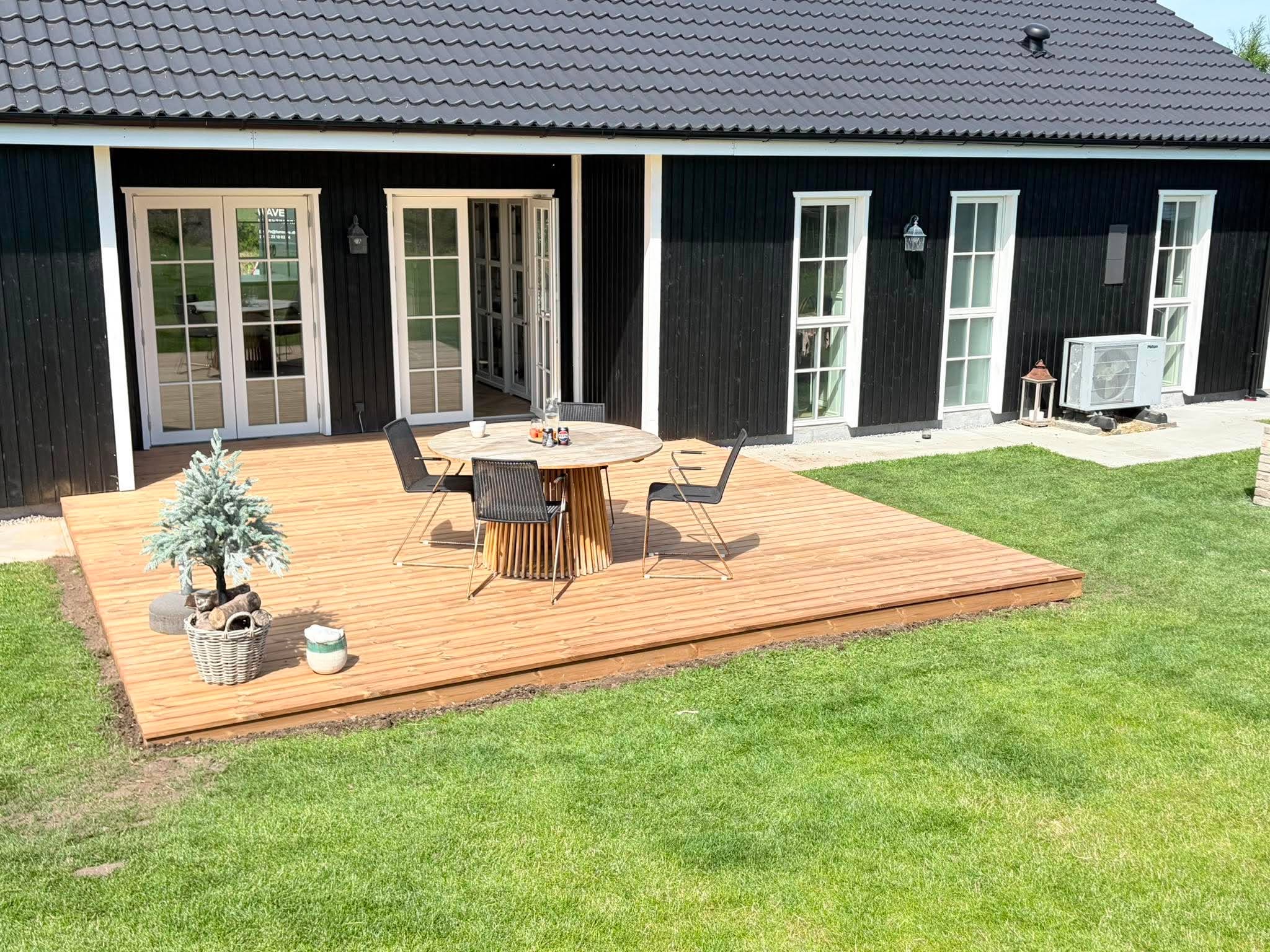 Færdig træterrasse ved et sort sommerhus