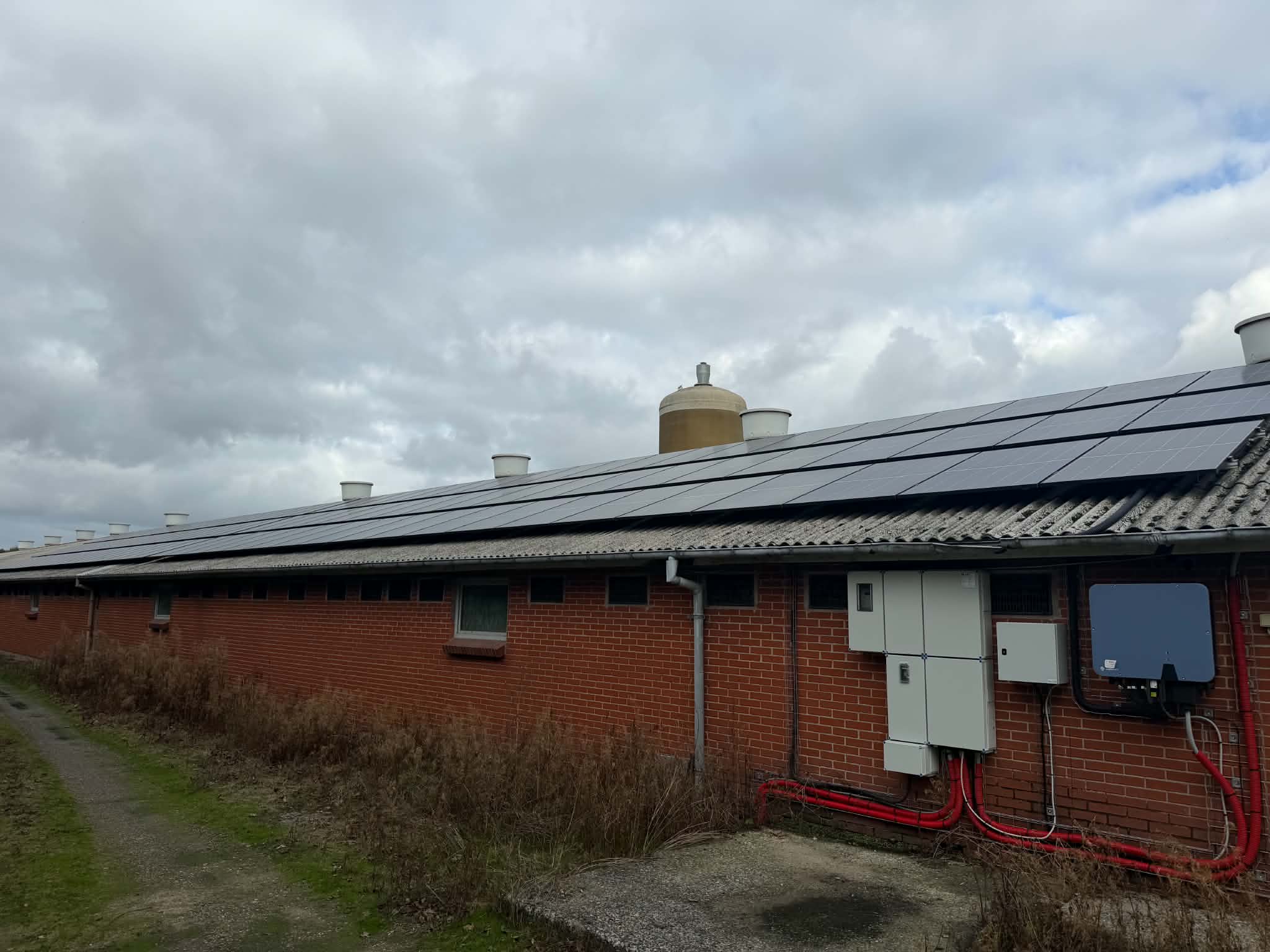 Stald med solceller på taget og inverter og tavler på væggen